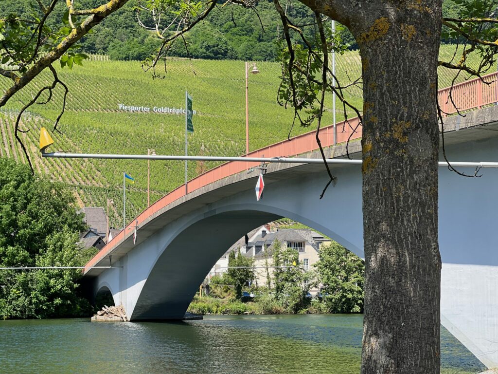 Red and gray concrete bridge over Germany's Rhine River leading into the Piesporter Goldtröpfchen vineyard
