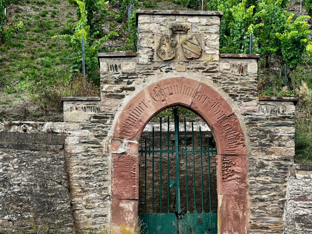 Stone arch with green metal gate leading into the Maximin Grünhaus monopole vineyard