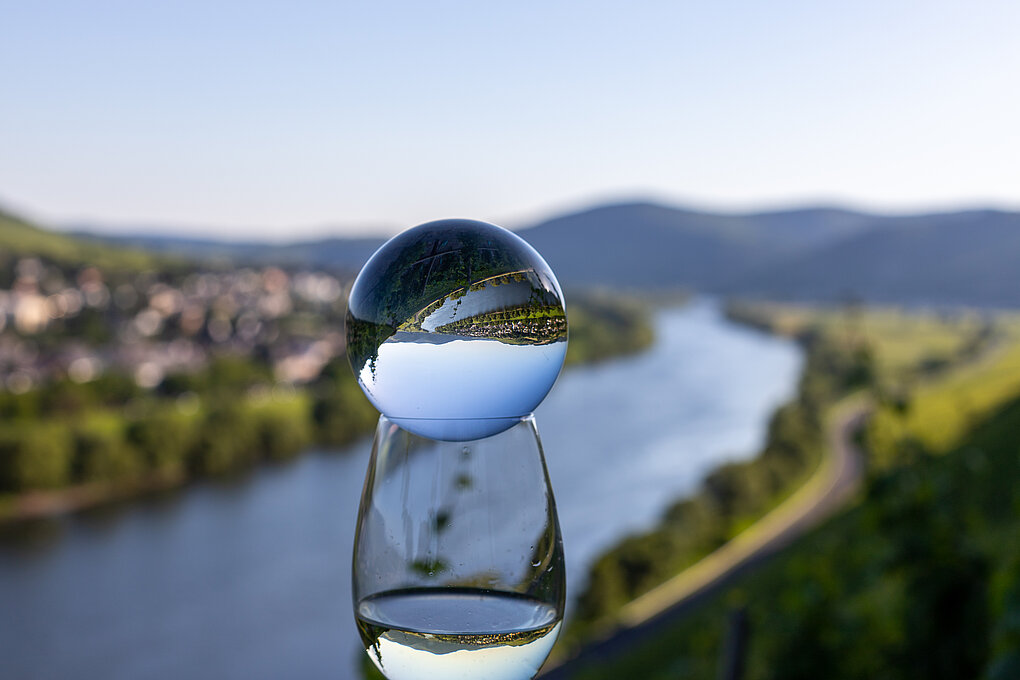 crystal ball sits atop a wine glass with white wine overlooking the Mosel River