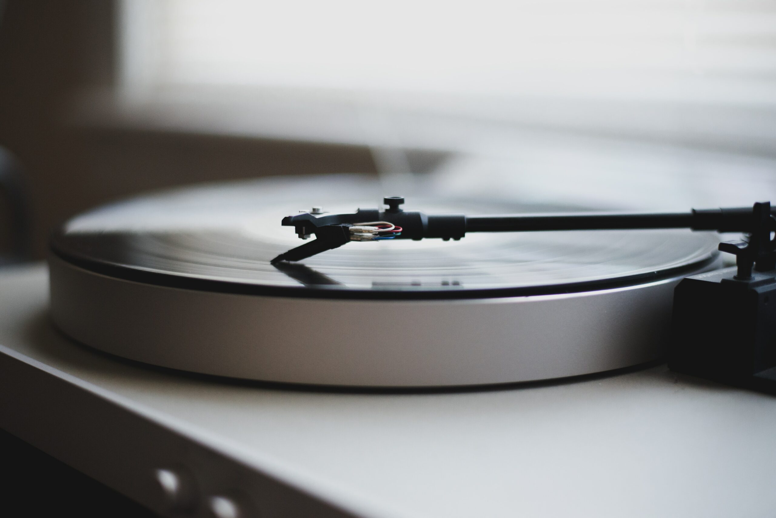 Black and white close up of a record player next to a window