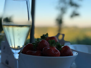 A glass of bubbling German sekt next to a bowl of strawberries