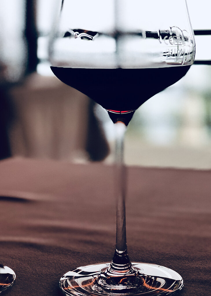 Macro of a glass of red wine on a red tablecloth against a lit window