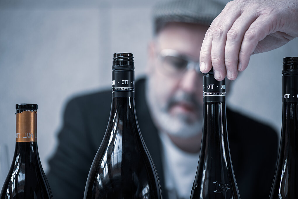 Sebastian Bördthäuser at Austrian Koch.Campus's Swine Wine event behind a row of wine bottles from Wagram winegrower Bernard Ott