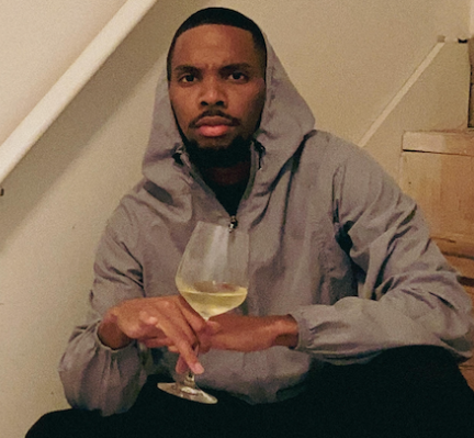 Mason Washington sits on a staircase with bottles of Riesling scattered around him.