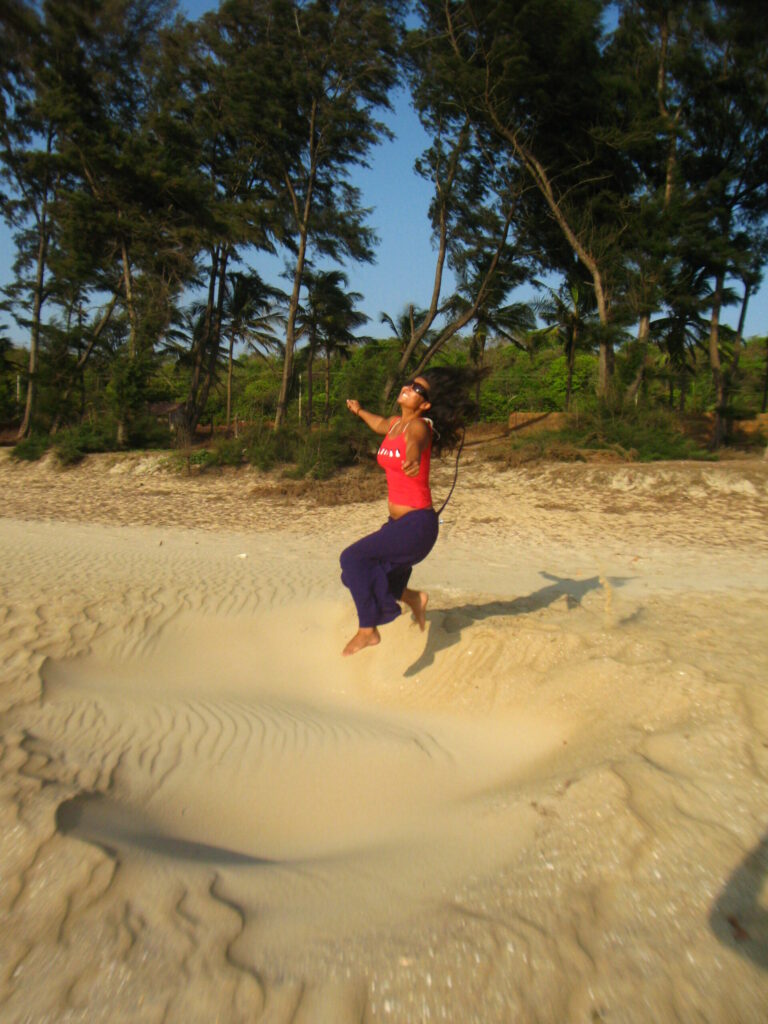 Woman jumping into a sandpit in tropical setting