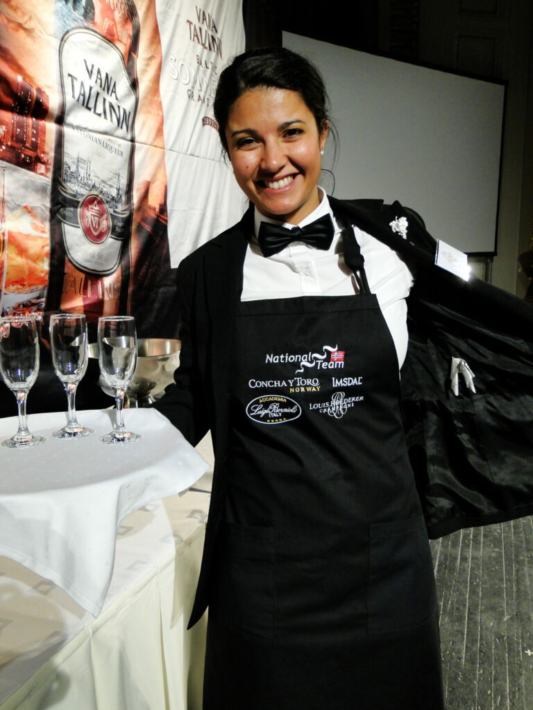 Sommeliere wearing an ASI apron and holding a serving tray with three empty wine glasses