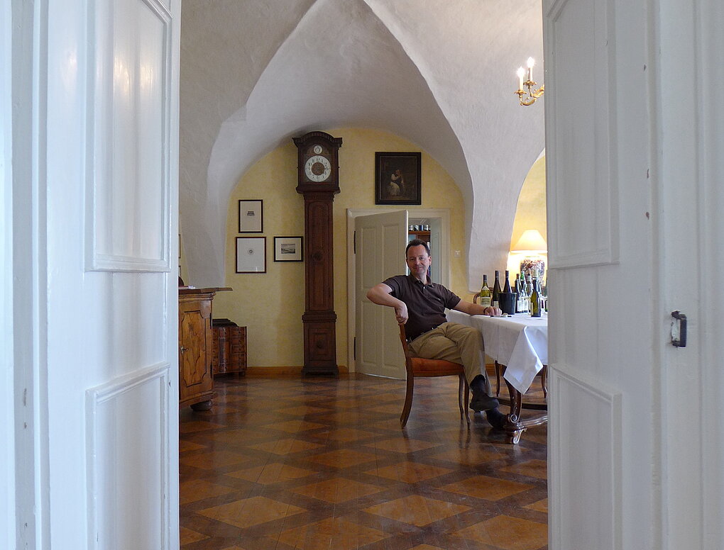 Austrian winemaker Michael Moosbrugger sis in his kitchen at a table with wine bottles.