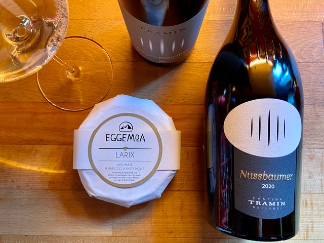 Alto Adige wine bottle from Kellerei Tramin beside a small round of wrapped Larix cheese from Eggemoa