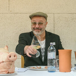 Wine writer Sebastian Bördthäuser at Austrian Koch.Campus's event holding a glass of Steiermark white wine next to a swine head.