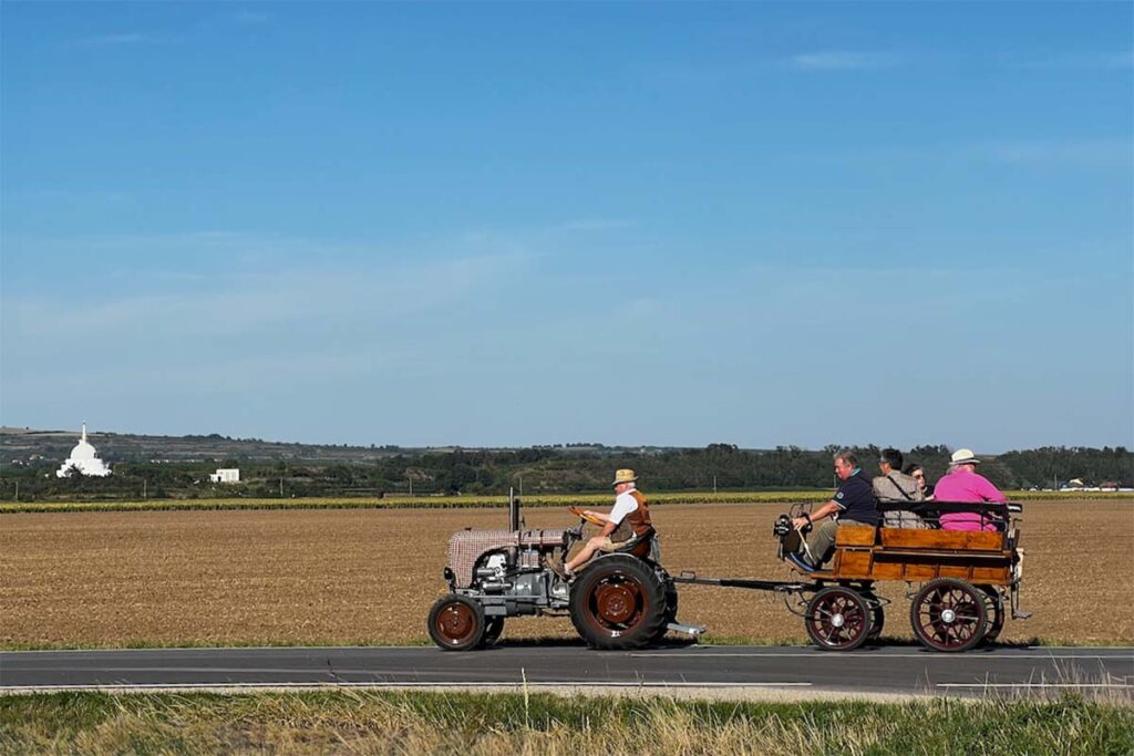 A photo of a tractor pulling three people across an Austrian vineyard. Contact TRINK magazine here.