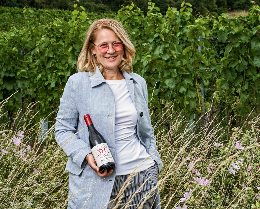 Carnuntum winemaker Dorli Muhr holding a bottle of her Blaufränkish wine