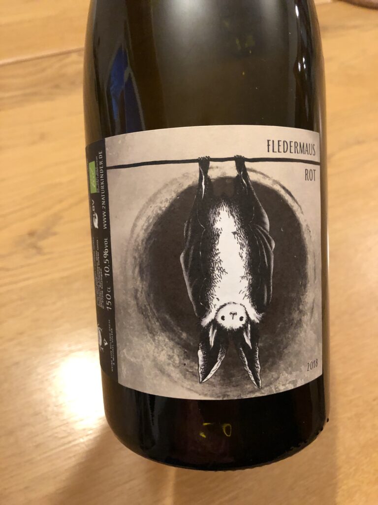 A black wine bottle with a brown label featuring a drawing of an upside down bat and the words FLEDERMAUS ROT