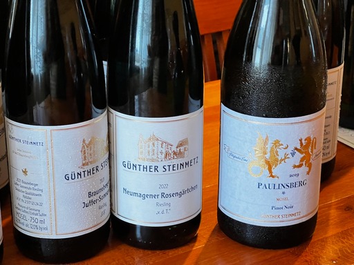 Three dark glass wine bottles with white labels, gold and black lettering reading GUNTERSTEINMETZ Neumagener Rosengärtchen "v.d.T.,