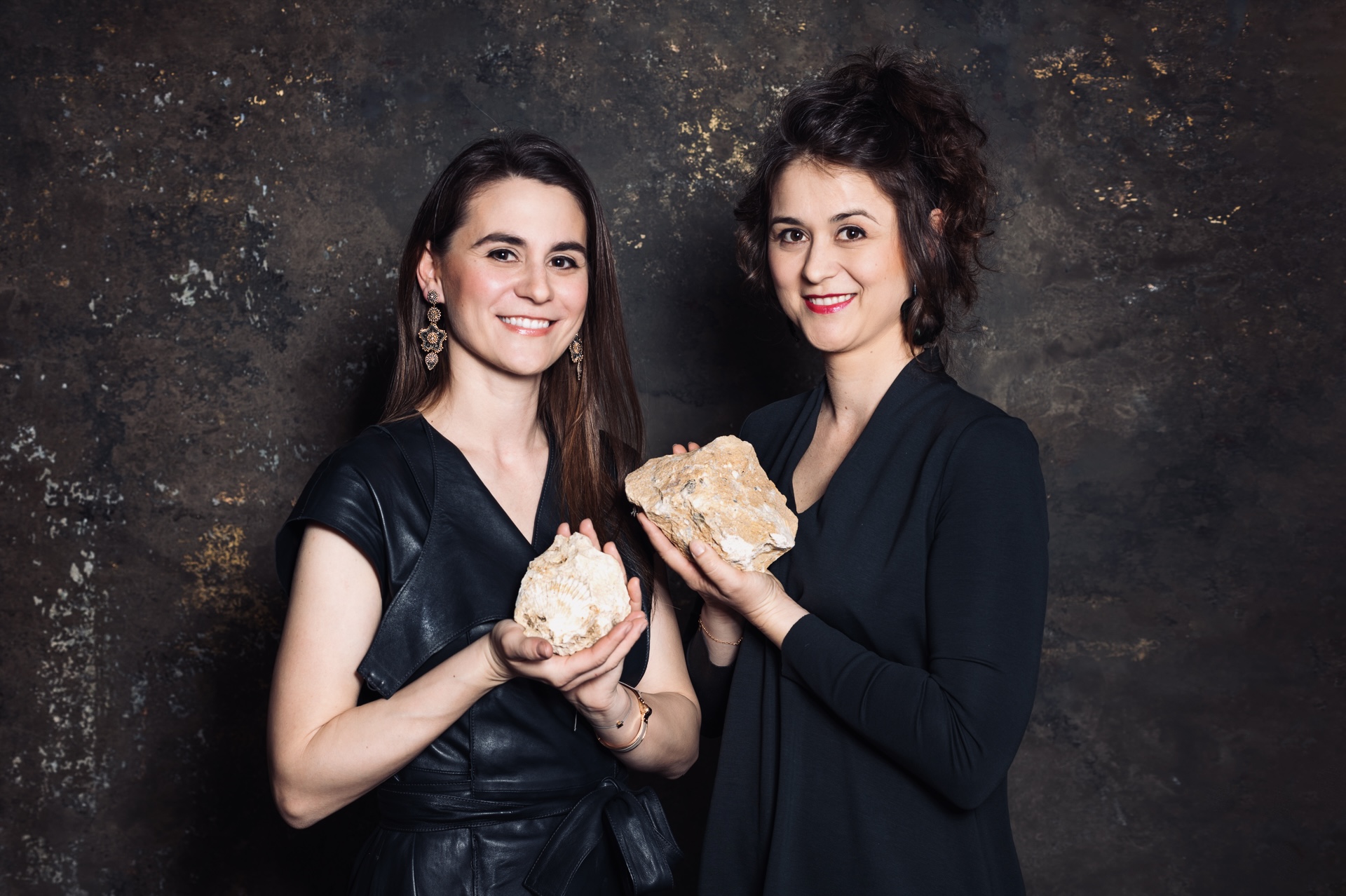 Two sister winemakers stand in Sopron wine cellar holding rocks