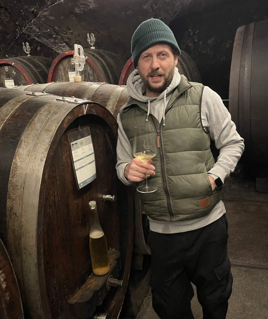 Kai Schätzel stands in his cellar, leaning against a wooden cask