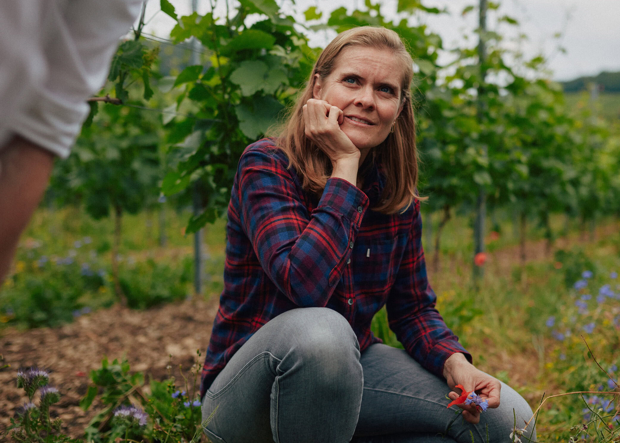 Meike Näkel sits in a vineyard, looking thoughtful