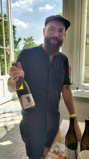 Bearded winemaker holding a bottle of natural wine at Karakterre