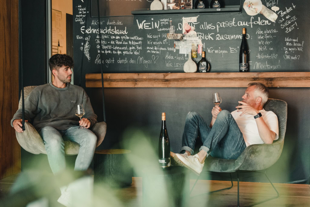 Franken vintners discuss stone casks in their vinothek while holding glasses