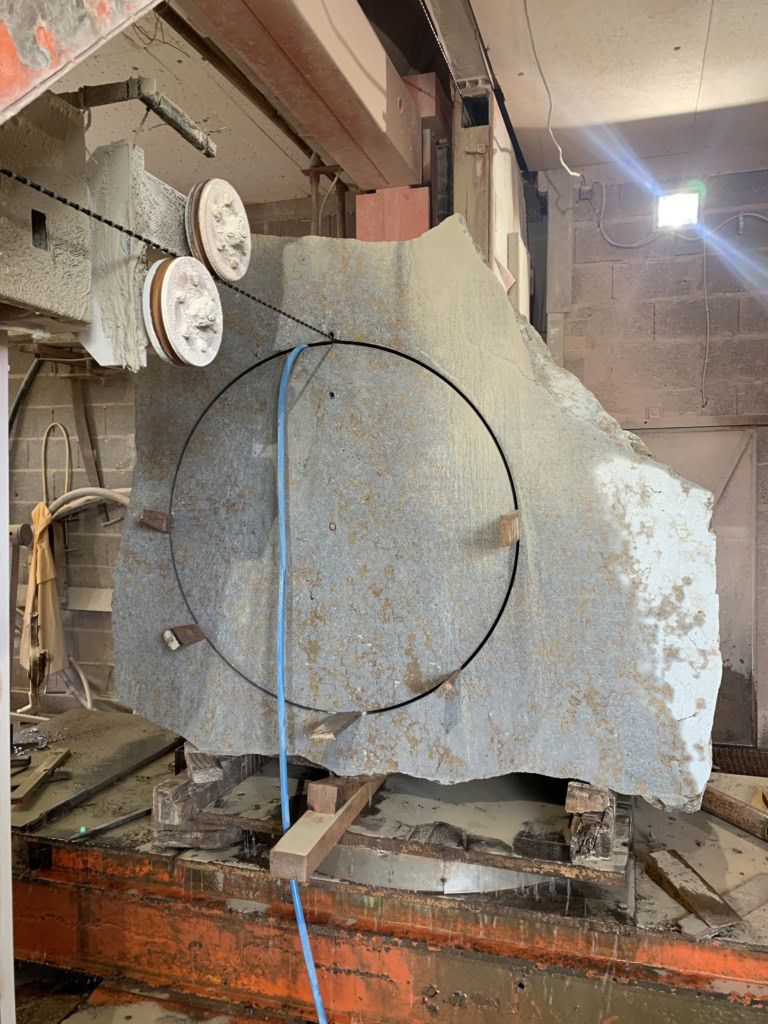 Slab of limestone for stone cask on orange lathe ready for cutting