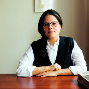 Cookbook author Luisa Weiss sits at wooden table with arms crossed