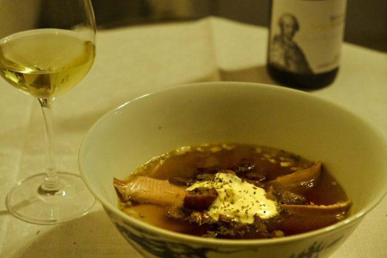 A bowl of fish soup next to a glass of Pfalz Riesling