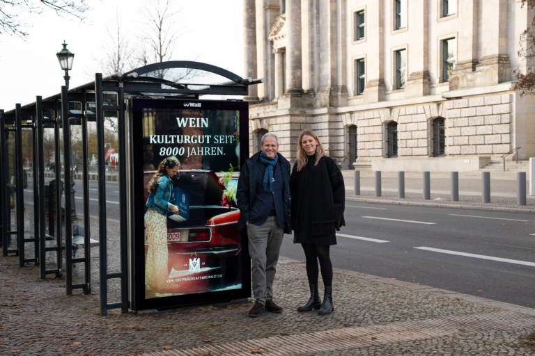 Two people stand in front of a digital billboard for the VDP cultural asset campaign.