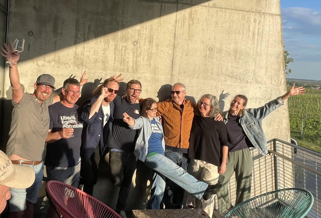 Pannobile group celebrates outdoors at sunset, smiling and enjoying each other's company. Photographed at Clause Preisinger's modernist estate.