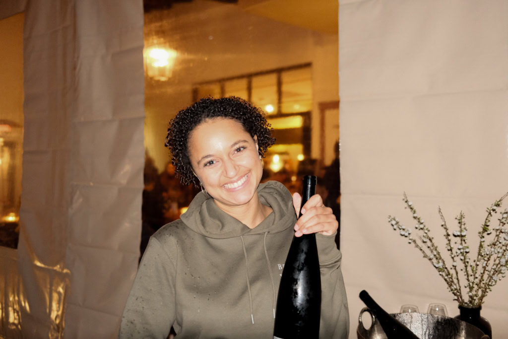 Smiling woman holding a wine bottle.